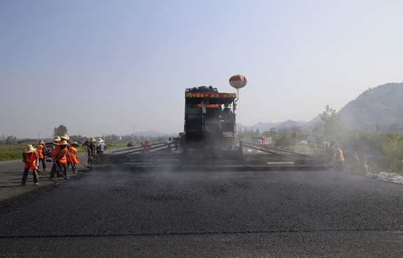 2019年8月，宜春經(jīng)開區(qū)S311路面攤鋪現(xiàn)場，工友們輔助路面兩側(cè)的分料、補窩等作業(yè)